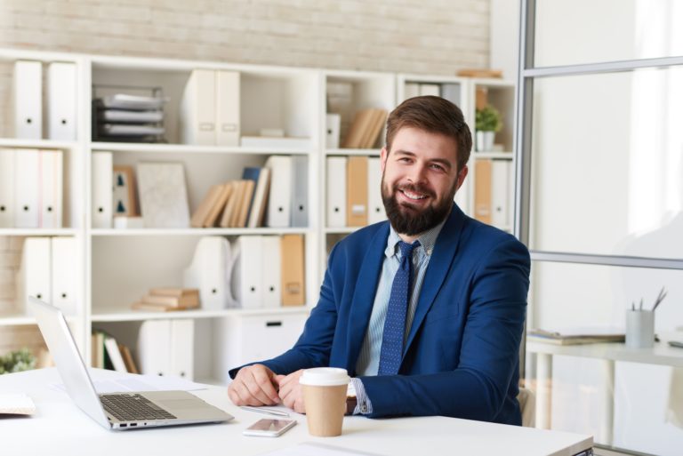 Smiling Business Person at Desk in Office